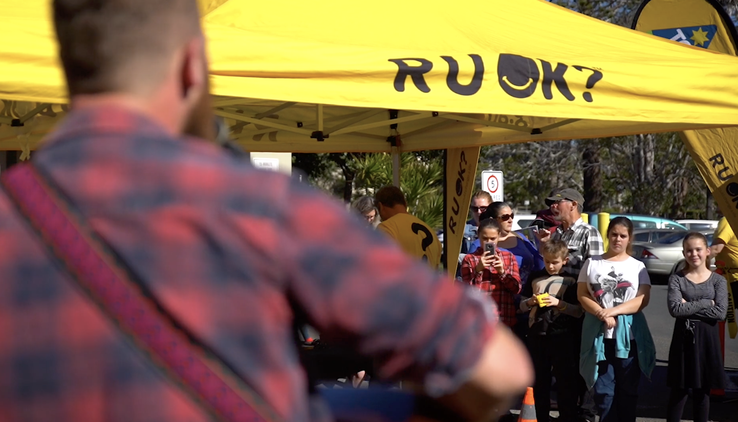R U OK? Father's Day event under a yellow branded tent with attendees gathered